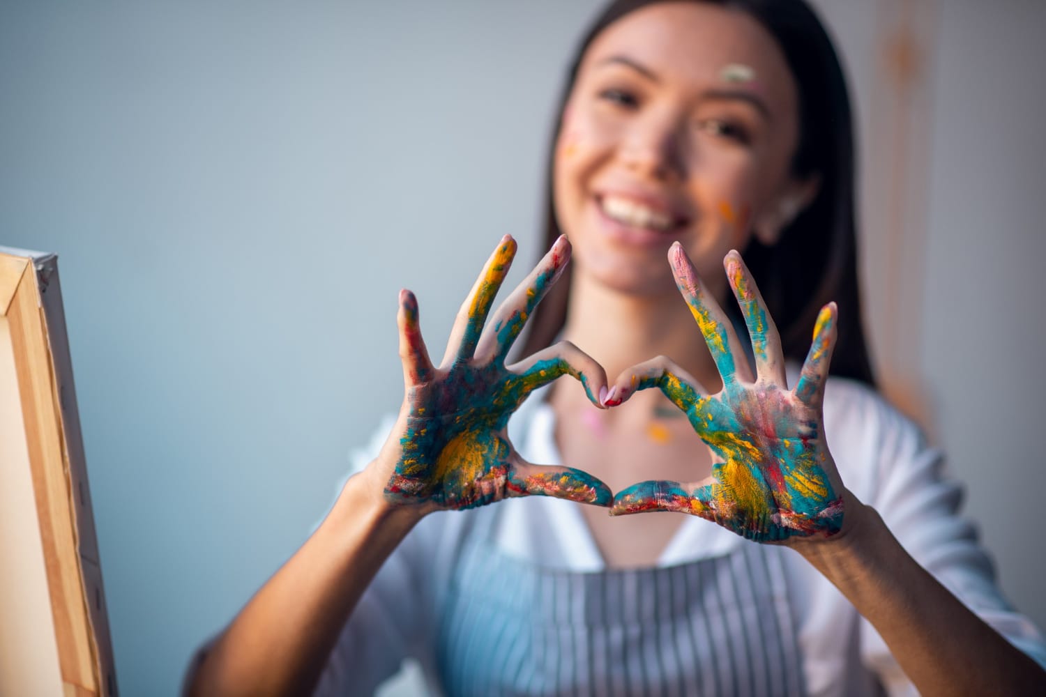 Jovem mulher fazendo um coração com a mão e estudando sobre repertorio sociocultural.