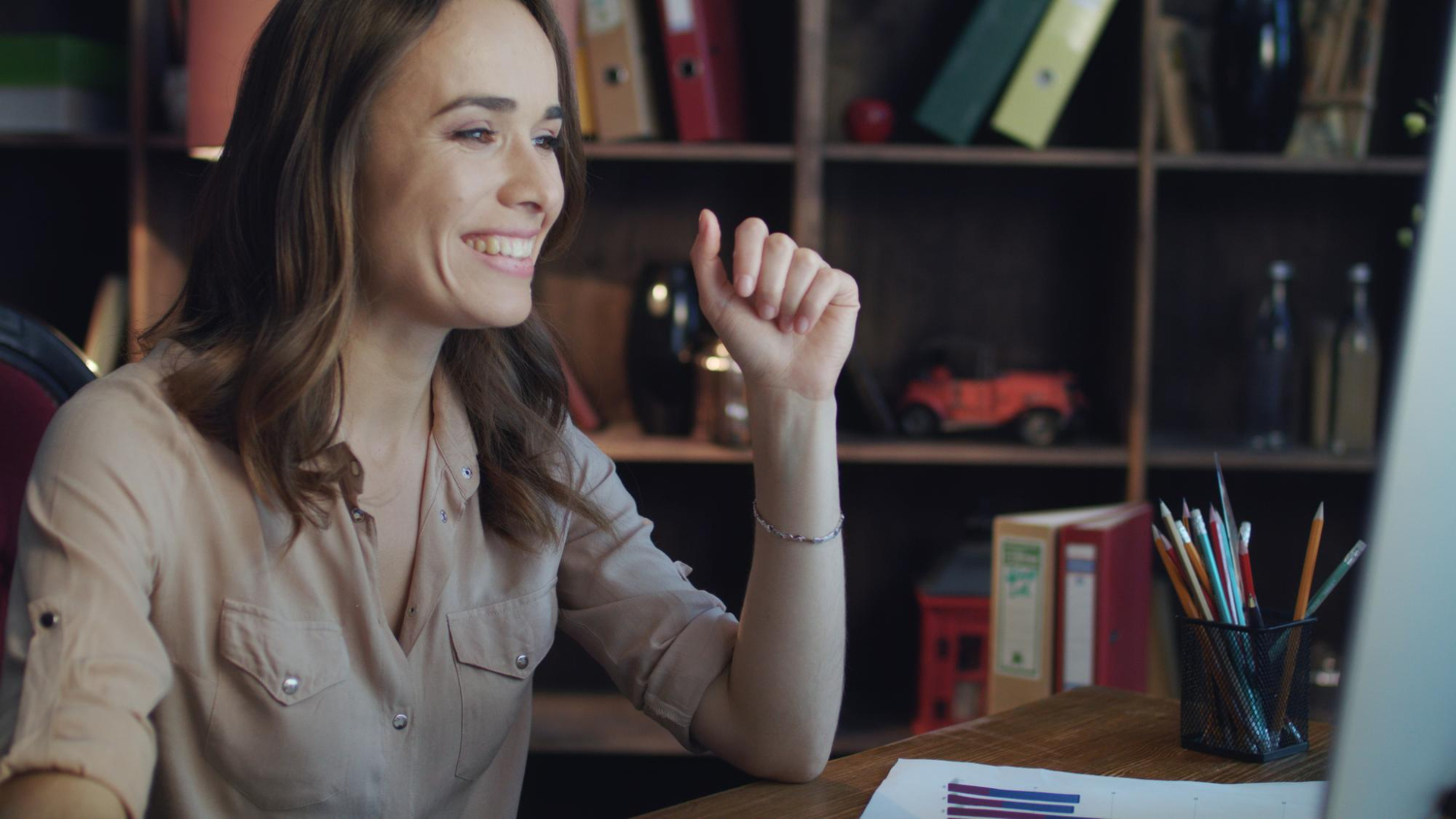 Mulher sorrindo em frenteo ao computador e lendo sobre dicas para apresentação online.