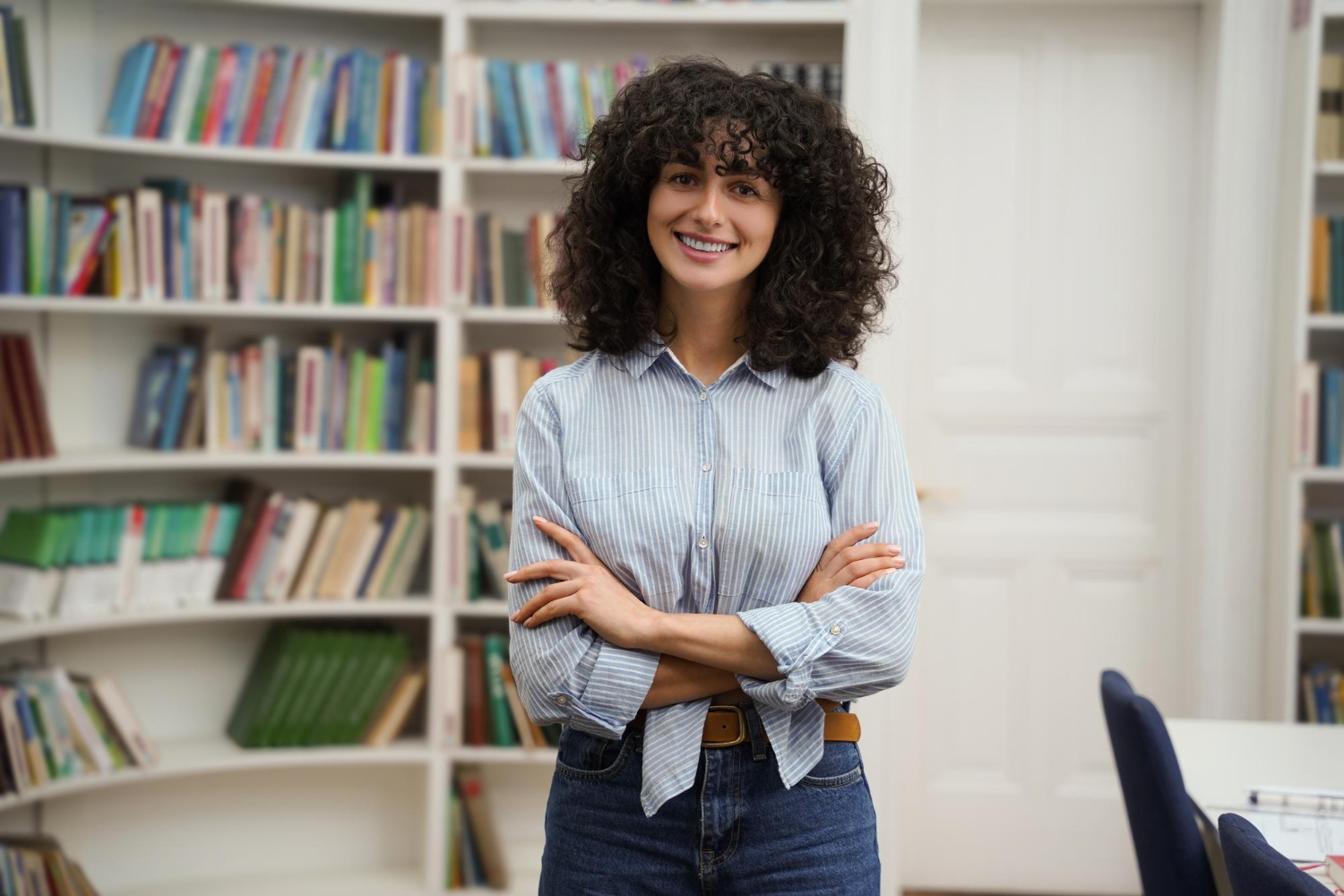 Mulher em pé em uma sala com livros descobrindo o que faz uma assistente social.