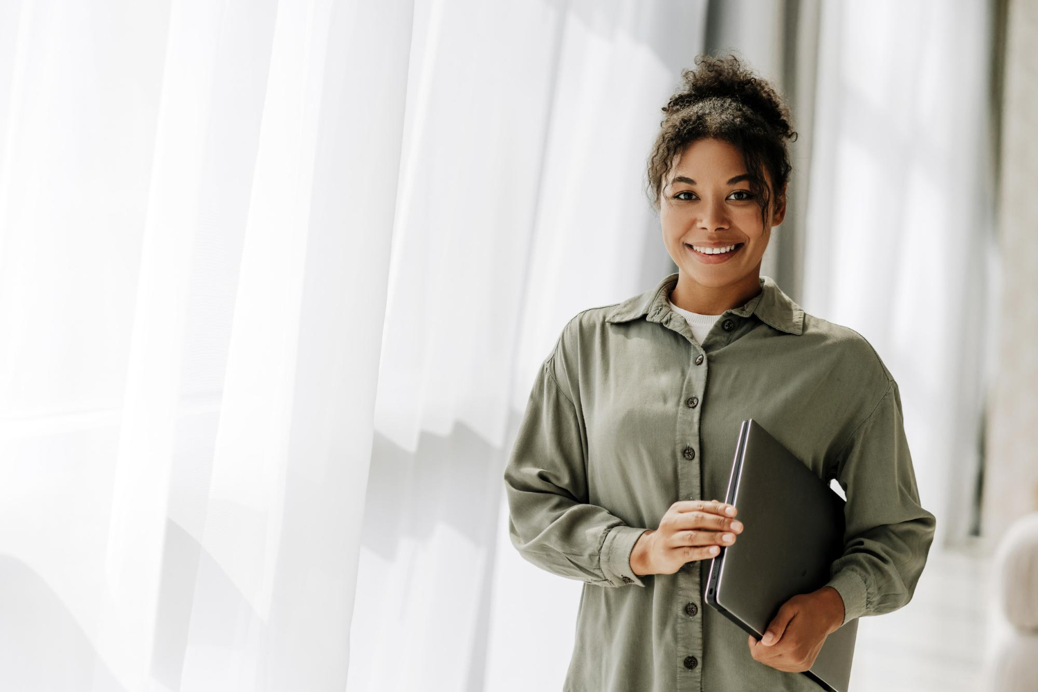 Mulher em pé sorrindo e pesquisando sobre quanto ganha um assistente social.