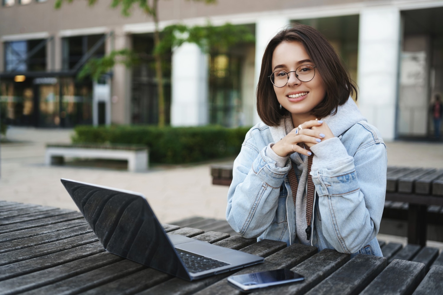 jovem estudante sentada com notebook e celular sobre a mesa